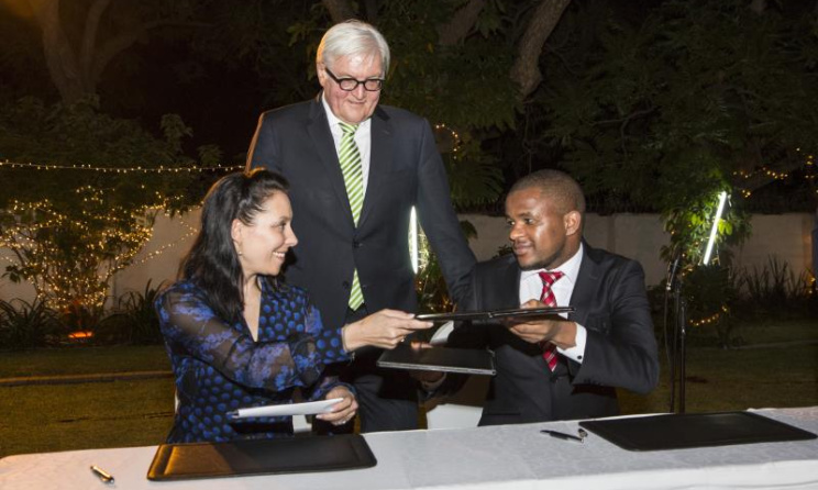 Eddie Hatitye (right) and Nathalie von Siemens (left) sign the MoU as German Foreign Minister Frank-Walter Steinmeier looks on.