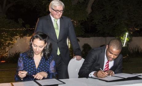 Eddie Hatitye (right) and Nathalie von Siemens (left) sign the MoU as German Foreign Minister Frank-Walter Steinmeier looks on.