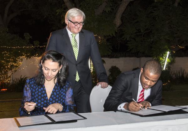 Eddie Hatitye (right) and Nathalie von Siemens (left) sign the MoU as German Foreign Minister Frank-Walter Steinmeier looks on.