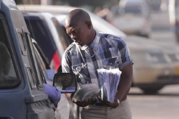 A vendor sells pirated music to motorists on the streets of Harare. Photo: The Herald