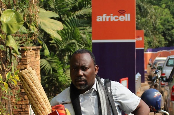 Richard Kawesa who protested in chains, on a mat outside the Africell ofiices. Photo:Chimpreports.com