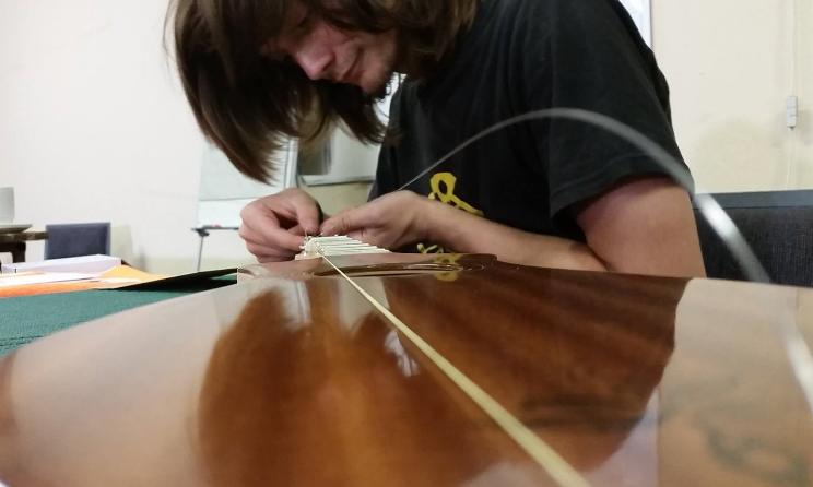 Un participant qui s'appliquer à placer les cordes de sa guitare.