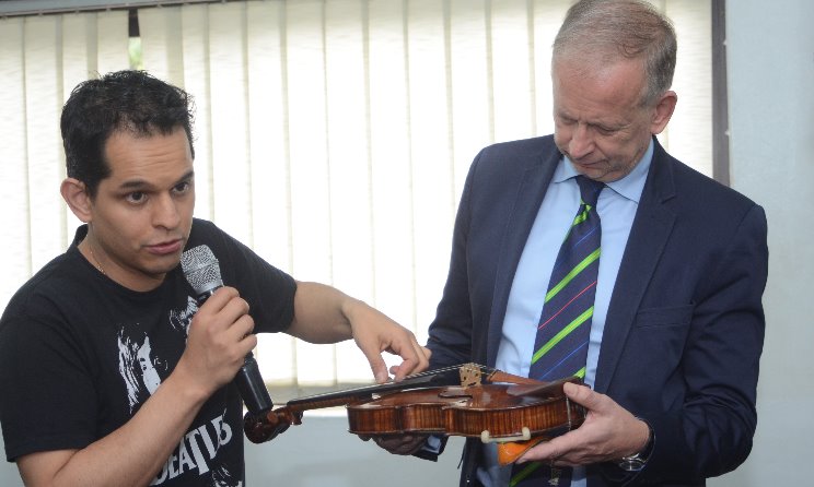 German consul-general Ingo Herbert, right, examines a violin.