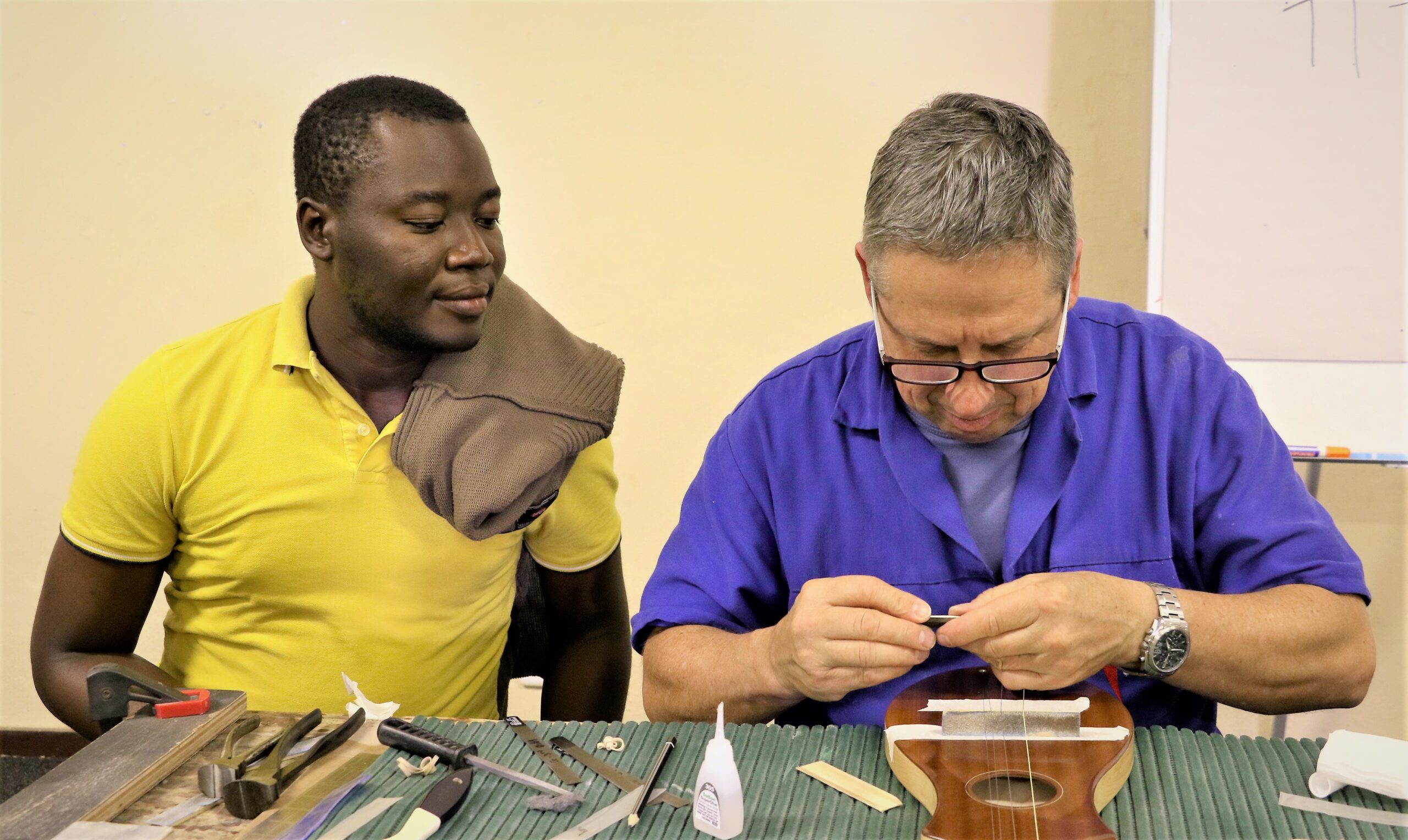 A participant watches a trainer crafting a dulcimer guitar during the first Instrument Building and Repair workshop in 2016. Photo: Music In Africa