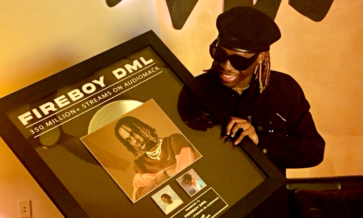 Fireboy DML posing for a photograph with his Audiomack plaque.