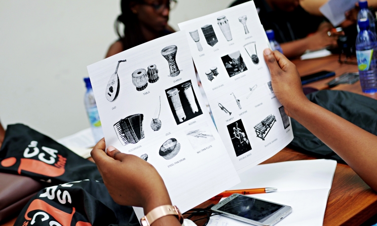 A Gender@Work participant pages through educational material with musical instruments. In 2023, the programme is expanding to include the online Music Business Management module. Photo: Music In Africa